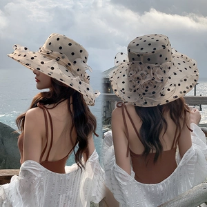 Detail view of beige sun hat with black polka dots and layered flower decoration
