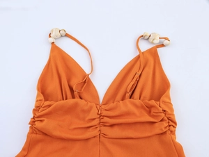 Vue détaillée d'une robe orange à col en V avec des perles décoratives à texture marbre