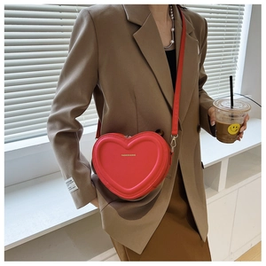 Dettaglio di un'elegante borsa a tracolla rossa a forma di cuore indossata da una modella