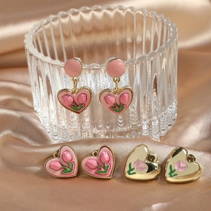 Macro shot of gold-plated tulip heart pendants and earrings on elegant champagne silk