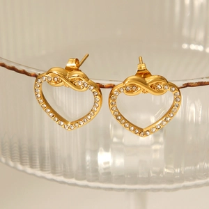 Close-up of gold heart earrings with infinity symbol and sparkling crystals