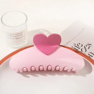 Macro detail of sweet pink heart-shaped hair claw clip on a decorative white ceramic tray