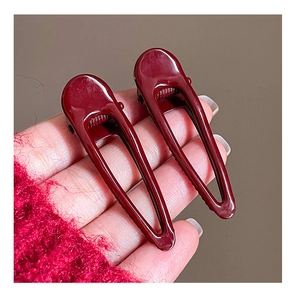 Detail shot of wine red geometric pleated hair clips with a silver metal spring mechanism