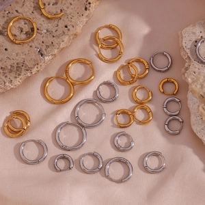 Vue macro de boucles d'oreilles créoles or et argent avec zircons sur tissu en soie