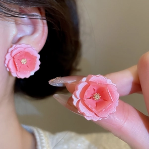 Gros plan de boucles d'oreilles fleurs en résine rose avec étamines dorées et argent