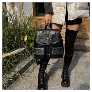 Détail d'un sac à dos vintage en similicuir noir avec boucles et rabat argentés