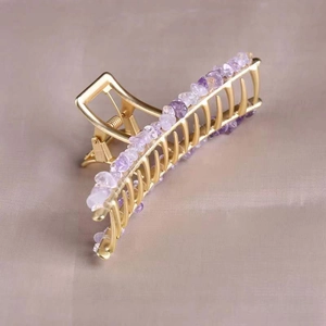 Detail of golden alloy hair claw with natural purple amethyst crystal beads decoration