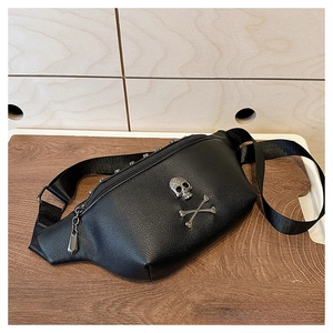 Close-up of black leather chest bag featuring metal skull emblem and rivet details