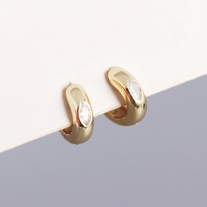 Macro shot of gold hoop earrings with teardrop-shaped zircon stones on white card