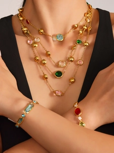 Vue détaillée d'un ensemble collier et bracelet doré orné de gemmes colorées et brillantes