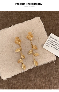 Détails de boucles d'oreilles fleurs et feuilles dorées avec une texture mate vintage