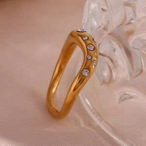 Detailed macro of 18K gold plated ring featuring curved wave design and five zircon stones