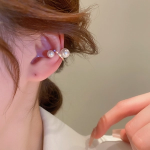 Detail of twisted gold ear cuff with two pearls and cubic zirconia on a female model