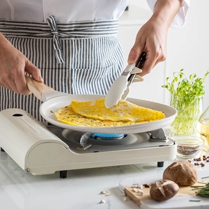 Silicone food tongs used for flipping an omelet in a pan with built-in stand support