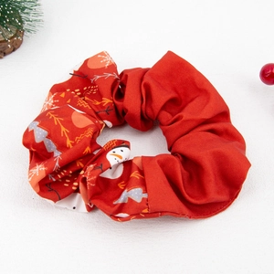 Close-up of red Christmas fabric scrunchie with festive snowman and snowflake patterns