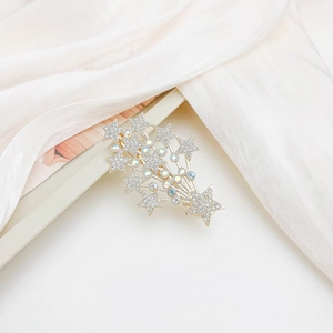 Detailed close-up of golden metal hair clip with sparkling stars and rhinestone details