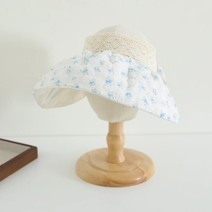 Détail d'un chapeau de soleil à fleurs avec dentelle beige et tissu en coton blanc