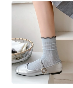 Detail of light blue ribbed socks with ruffled cuffs worn with silver Mary Jane shoes