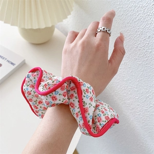 Floral fabric scrunchie with pink floral pattern and rose red trim worn on a wrist