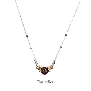 Detailed view of tiger's eye stone pendant with golden metal beads on a sleek chain
