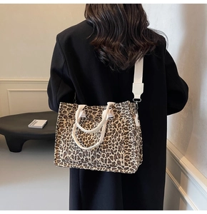 Model wearing a leopard print canvas tote bag with a wide strap in a modern interior setting