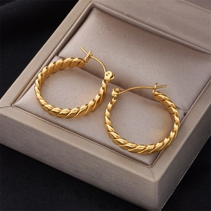 Pair of gold-tone braided twist hoop earrings displayed in a velvet jewelry box