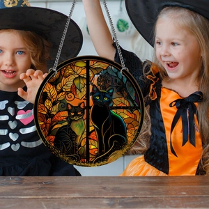 Detail showing two black cats sitting by autumn leaves on a round Halloween suncatcher