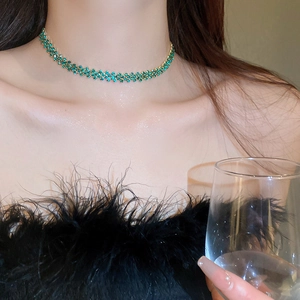 Dettaglio di collana girocollo in cristallo verde smeraldo con fascia in metallo dorato