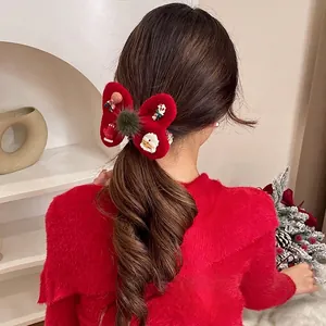 Christmas red plush bow hair tie with pom-pom and festive resin charms on a model hairstyle