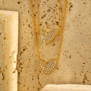 Detail view of double-layered gold heart necklace with micro-paved zircons on stone
