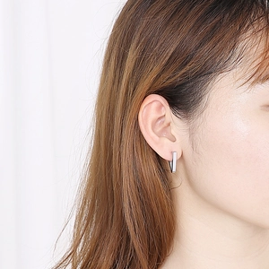 Close-up of minimalist silver V-shaped geometric stud earring worn on earlobe
