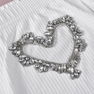 Dettaglio di decorazione a cuore in strass argento su tessuto a pieghe bianco