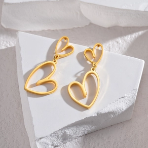 Vintage style matte 18K gold hollow heart earrings displayed on minimalist stone props