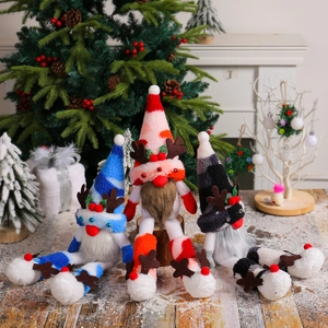 Three Christmas long-legged gnomes with reindeer antlers sitting on a wooden festive table
