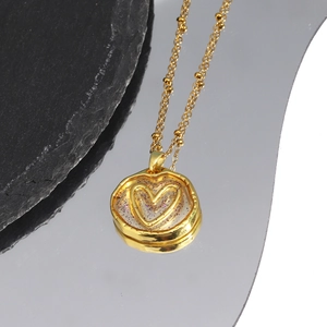 Detail of gold heart pendant with glitter inlay on black stone and mirror surface