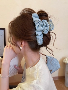 Detail of light blue polka dot heart hair claw clip on model's head with elegant styling