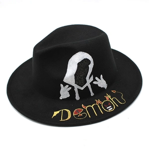 Detail of street-style black wool fedora featuring silver graffiti and demon embroidery