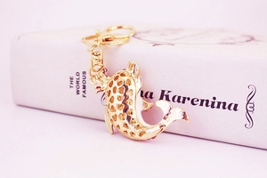 Detail of golden dolphin keychain with heart cut-outs resting on a book cover