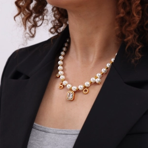 Vintage geometric pearl necklace with 18k gold-plated charms on a professional model