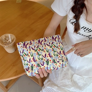Detail of canvas tulip makeup bag with floral print and brand label in a cafe setting