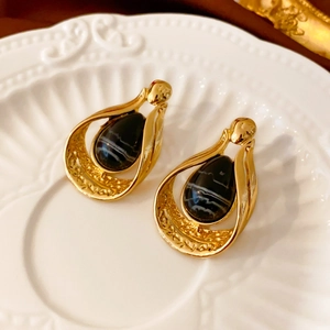 Vintage gold drop earrings with black striped faux agate displayed on ceramic plate