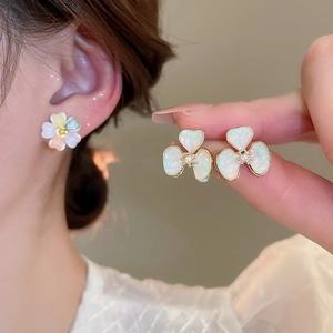Close-up of iridescent floral stud earrings with pearl center and 18k gold plating