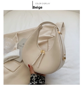 Detail view of beige crescent moon bag with smooth leather and gold metal hardware