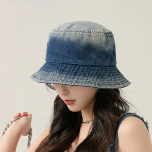 Detailed view of washed denim bucket hat with blue gradient finish and metal rivets