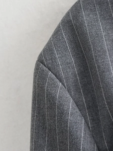 Close-up of fine sewing detail and white pinstripe texture on a dark grey wool blazer