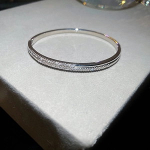 Détail d'un bracelet vague argenté serti de zircons fins sur un support en velours gris