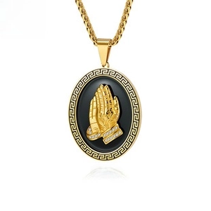 Macro shot of praying hands gold pendant with Greek fret edge and black background
