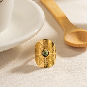 Detailed close-up of a vintage bohemian gold ring with green turquoise and ornate carvings