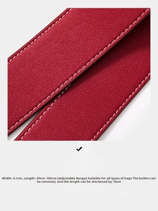 Macro view of red pebble leather bag strap with white stitching and adjustable length