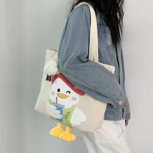 Detail of canvas tote bag featuring cartoon duck print and 3D plush duck feet accessory